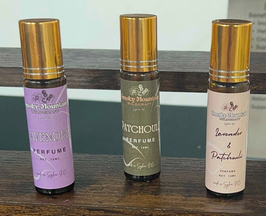 Front view of three roller bottles of an essential oil fragrance / perfume. Bottles are amber roller bottles with a gold cap.