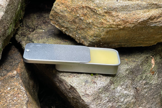 Side view of a sliding silver tin filled with organic lip balm, a natural skincare product infused with beeswax and soothing oils.